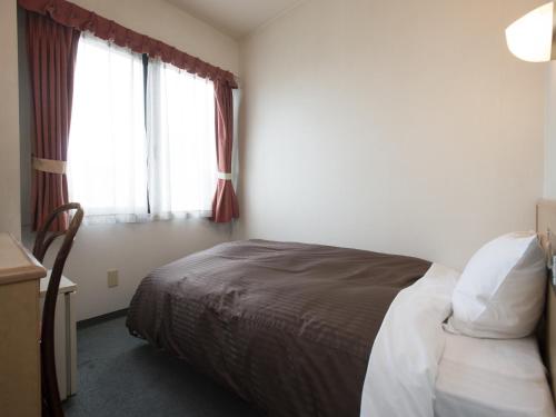 a hotel room with a bed and a window at Himeji Green Hotel Sakamoto in Himeji