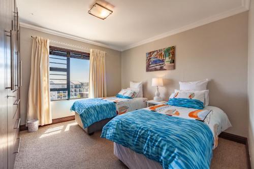a bedroom with two beds and a window at Luxury 3 bedroom Duplex Penthouse with communal swimming pool in Bloubergstrand