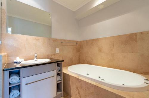 a bathroom with a tub and a sink at Pearl Valley Golf lodge in Paarl