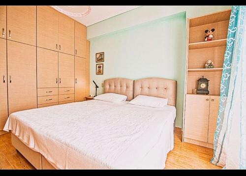 a bedroom with a large white bed with wooden cabinets at Κatakolo Luxury Seaside House & Garden in Katakolo