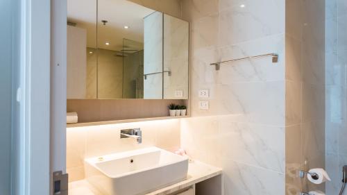 a white bathroom with a sink and a mirror at Cassia Residences in Bang Tao Beach