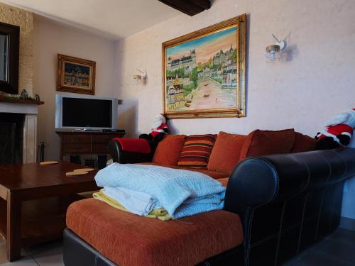 ein Wohnzimmer mit einem Sofa und einem TV in der Unterkunft Ma Gentilhommière in Croutoy