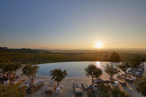 a pool with lounge chairs and a sunset in the background at Château Capitoul in Narbonne