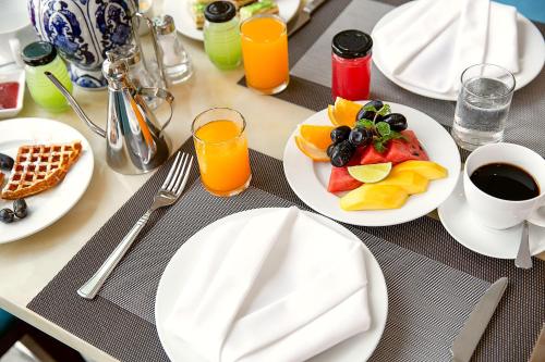 a table with white plates of food and orange juice at TGT BEACH HOTEL in Da Nang