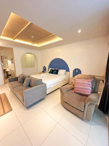 a bedroom with a bed and two couches at Costa Beach Residence & Jacuzzi in Sattahip