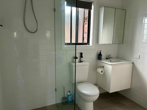 a white bathroom with a toilet and a sink at Lola’s@lennox in Lennox Head