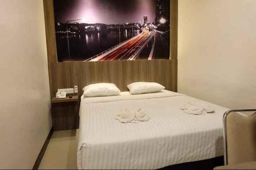 Un dormitorio con una cama blanca con una foto en la pared en HOTEL MY HOME SINTANG en Sintang