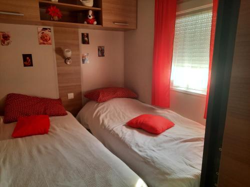two beds in a bedroom with red pillows at Mobilhome 8 pers in Fréjus