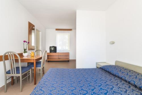 een slaapkamer met een bed en een tafel en een eetkamer bij Apartments Polynesia Plava Laguna in Umag
