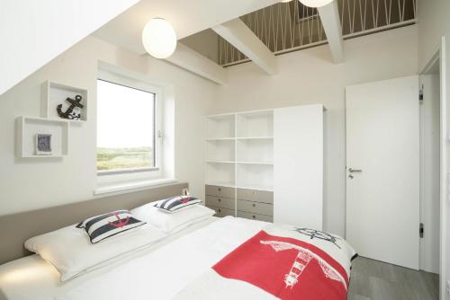 a white bedroom with a large bed with two pillows at MeerVerliebt C in Hörnum