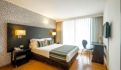 ボゴタにあるHospedium Hotel Urban Bogotá Javerianaのベッドとテレビが備わるホテルルームです。