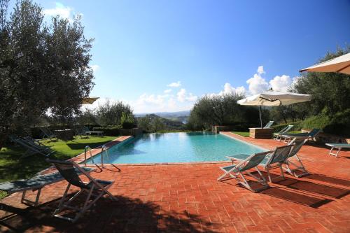 a swimming pool with two chairs and an umbrella at Borgo Poneta in Barberino di Val dʼElsa