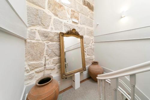 pasillo con pared de piedra y espejo en Palácio Fenizia Lux Apartments, en Oporto