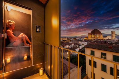 una donna seduta su un balcone con vista sulla città di Hotel Bellavista a Firenze