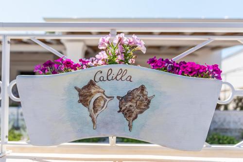a flag with the word calida on it next to flowers at Terrazza e Conchiglie in Torre Suda