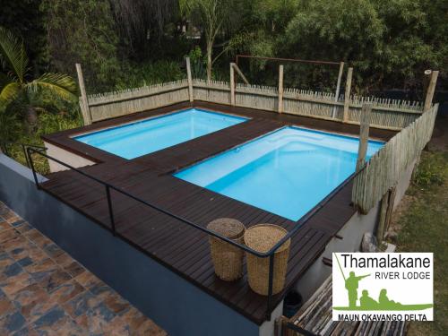 a swimming pool on a wooden deck with at Thamalakane River Lodge in Maun