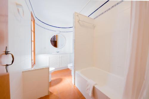 a white bathroom with a tub and a toilet at Villas Es Brucs in Cala Morell