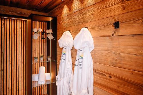 a bathroom with white robes hanging on a wooden wall at Tiny House mit Sauna - am Main in Wipfeld
