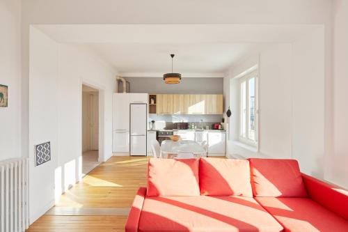 un salon avec un canapé rouge et une cuisine dans l'établissement Charme et confort entre jardin des plantes et LU, à Nantes