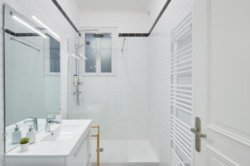 une salle de bain blanche avec un lavabo et une douche dans l'établissement Charme et confort entre jardin des plantes et LU, à Nantes