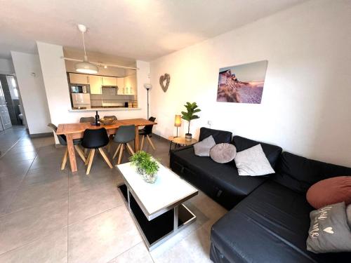 ein Wohnzimmer mit einem schwarzen Sofa und einem Tisch in der Unterkunft Breda 4a in Torroella de Montgrí