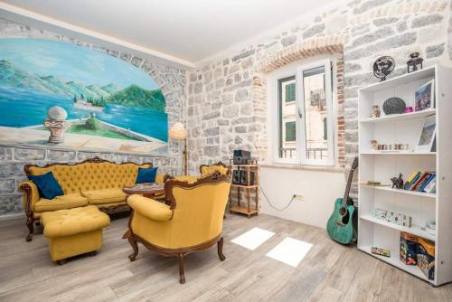 sala de estar con sofá amarillo y pared de piedra en CENTRUM HOSTEL, en Kotor
