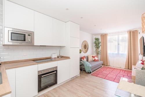 eine Küche mit weißen Schränken und ein Wohnzimmer in der Unterkunft Luxury flat Chueca I in Madrid