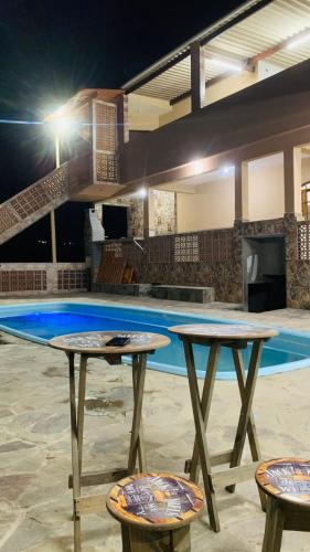 duas mesas e dois bancos em frente a uma piscina em Chácara Recanto das Pedras em Guarulhos