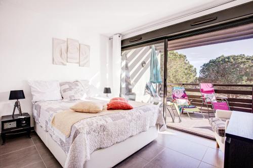 a bedroom with a bed and a balcony with chairs at VERT PARADIS - Vue apaisante sur GOLF, Pins Parasols, 2è étage - 80 m2 dont Terrasse avec Pergola, 2 chambres, 3ét iles, 3 CLIM, WIFI - Piscine, Parking et Park à vélos, Ascenseur - en Option Linge, Ménage - Pistes cyclables, Mer à proximité in Saint-Cyprien
