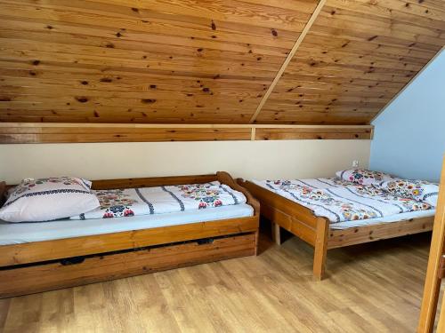 two beds in a room with wooden ceilings at Dudkowe Domki w Beskidach- Relaks z Balią i Apiterapią in Jeleśnia