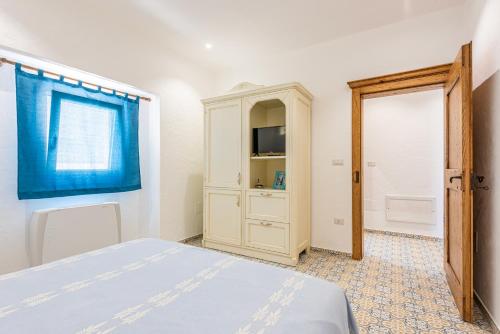 a bedroom with a bed and a cabinet and a window at Terrazza e Conchiglie in Torre Suda