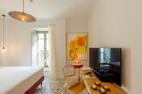 a bedroom with a bed and a table with a television at CasAunoE Boutique Hotel in Olbia