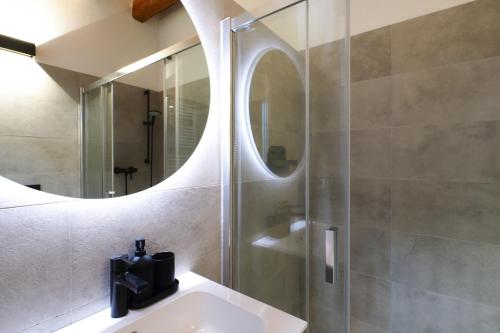 een badkamer met wastafel en douche met spiegel bij Primopiano - Zumbini in Milaan