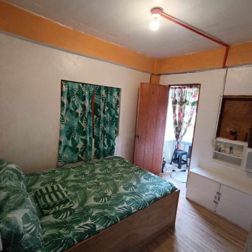 a bedroom with a bed with a green comforter at Titaays Surfers Inn in Baras