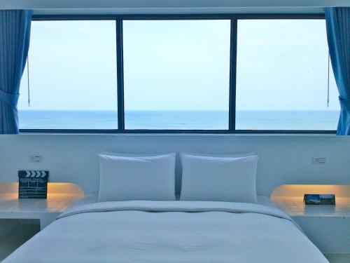 a bedroom with a large white bed with two windows at Sea Shore Hotel in Manzhou
