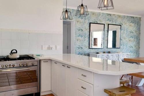 une cuisine avec un grand comptoir blanc et un évier dans l'établissement House Khasia- on the Golden Mile, à St Helena Bay