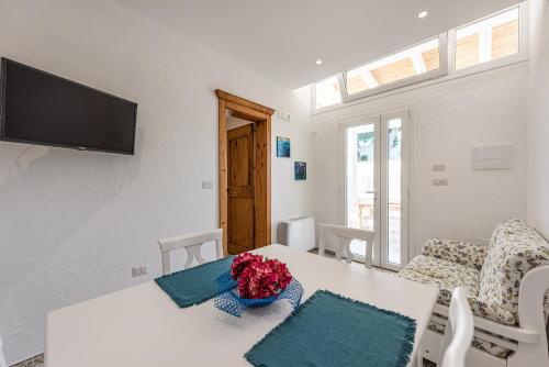 a white living room with a table and a tv at Terrazza e Conchiglie in Torre Suda