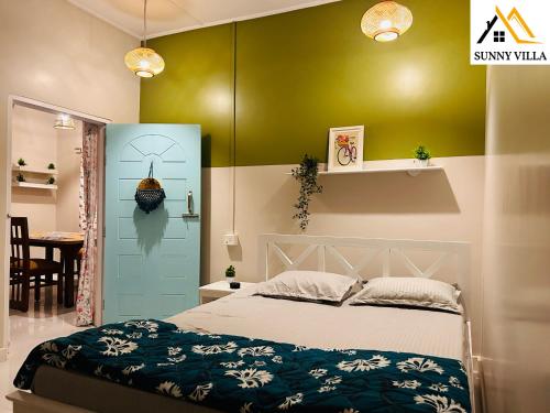 1 dormitorio con cama y pared verde en Sunny Villa Cottage en Sivasagar