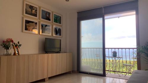 a living room with a television and a sliding glass door at Apartamento Los Guirres in Tazacorte