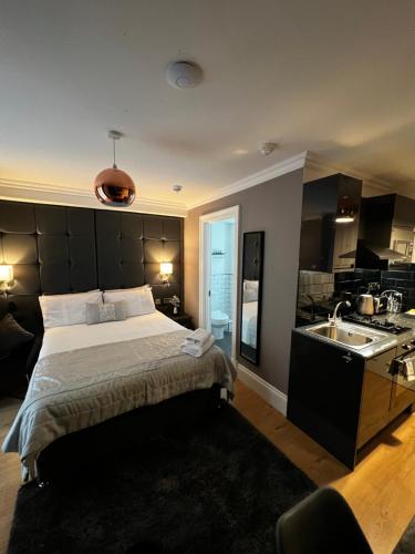 a bedroom with a large bed and a kitchen at Amani Apartments - Glasgow City Centre in Glasgow