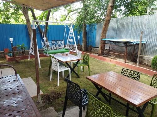 un patio con mesas, sillas y un columpio en Blue Diamond Service Apartments, en Pune