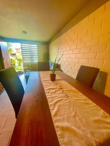 Casa 2 habitaciones en Labranza - Temuco في تيموكو: طاولة خشبية طويلة مع كراسي ونبات الفخار