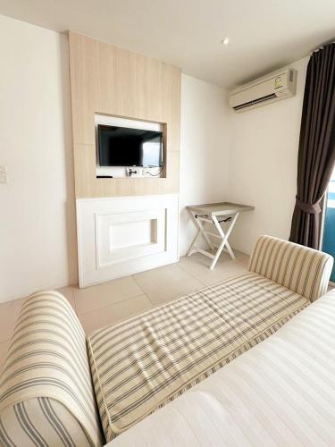a bedroom with a bed and a tv and a table at Costa Beach Residence & Jacuzzi in Sattahip