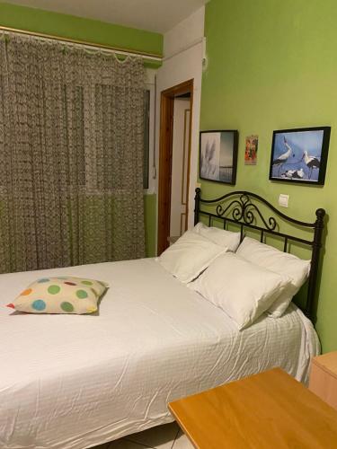 a bedroom with a bed with white pillows and green walls at Maria's rooms CHANTZARA SPYROPOULOS Flats to Let-City Center in Igoumenitsa