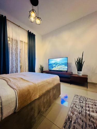 a bedroom with a bed and a flat screen tv at luxury home royal breeze in Ras al Khaimah