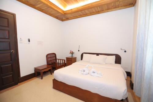 Un dormitorio con una cama con dos cisnes. en Villa KiengKham晶康民宿, en Luang Prabang