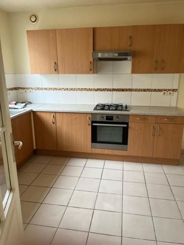 - une cuisine avec des placards en bois et une cuisinière dans l'établissement Maison 6 couchages Lormont proche tram, à Lormont