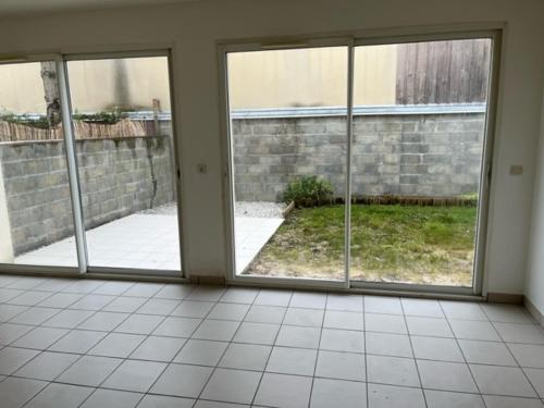 une pièce vide avec trois fenêtres et un mur de briques dans l'établissement Maison 6 couchages Lormont proche tram, à Lormont