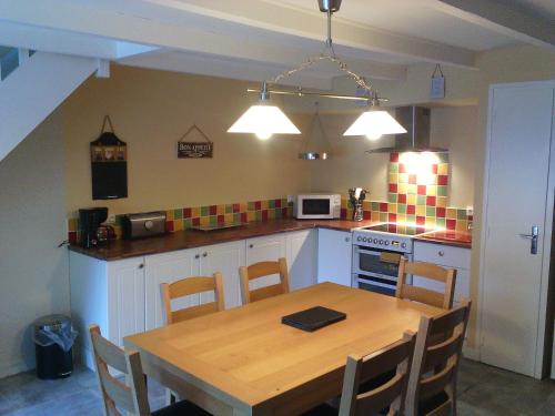 a kitchen with a wooden table and a table and chairs at Gîte à la Ville in Rostrenen