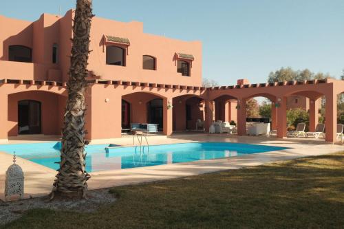 a villa with a swimming pool in front of a house at Villas Green in Marrakech